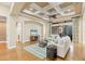 Spacious living room featuring hardwood floors, coffered ceilings, comfortable seating, and a view to the outdoor patio at 7665 Portstewart Dr, Lakewood Ranch, FL 34202