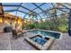 Enclosed pool and spa area featuring brick pavers, comfortable seating, and peaceful views of surrounding greenery at 7665 Portstewart Dr, Lakewood Ranch, FL 34202