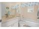 Well-lit bathroom with a tub, toilet, single sink vanity, and coral-themed accents at 803 Coral Bean Cv, Venice, FL 34293