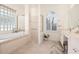 Elegant bathroom with a soaking tub, glass block window, and separate shower area at 803 Coral Bean Cv, Venice, FL 34293