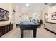 Spacious game room with pool table, tall ceilings, bright lighting, and elegant decor at 803 Coral Bean Cv, Venice, FL 34293