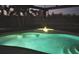 Well-lit swimming pool with a fountain feature for a relaxing evening atmosphere at 803 Coral Bean Cv, Venice, FL 34293