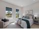 Relaxing bedroom features large windows, an accent chair, neutral decor and an inviting bed with decorative pillows and throw at 8364 Sea Glass Ct, Sarasota, FL 34240