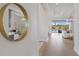 Bright hallway with wood floors leading to a living area, with a decorative mirror on the wall at 8364 Sea Glass Ct, Sarasota, FL 34240