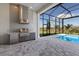 Covered outdoor kitchen with stainless steel grill and refrigerator, with pool view at 8364 Sea Glass Ct, Sarasota, FL 34240