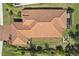 Overhead shot of a home's terracotta tile roof with a screened lanai, outdoor seating, and lush landscaping on a well-manicured lawn at 10802 Seasons Way, Palmetto, FL 34221