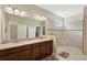 Modern bathroom with double sinks, granite countertop, and glass walk-in shower at 10802 Seasons Way, Palmetto, FL 34221