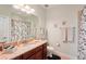 Well-lit bathroom featuring a granite countertop vanity, a large mirror and a shower with a decorative curtain at 10802 Seasons Way, Palmetto, FL 34221