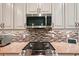 Modern kitchen with stainless steel appliances, mosaic backsplash, cooktop, granite countertops, and elegant white cabinets at 10802 Seasons Way, Palmetto, FL 34221