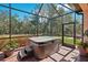 Screened-in patio featuring a luxurious hot tub, brick flooring, and views of the private backyard at 10802 Seasons Way, Palmetto, FL 34221