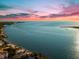 An aerial view features calm blue water and a pink and orange sunset along the waterfront at 116 Garden Ln, Sarasota, FL 34242