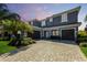Elegant gray home featuring a three-car garage, paver driveway, tile roof, and professionally landscaped yard at 12022 Medley Ter, Lakewood Ranch, FL 34211