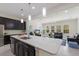 Open concept kitchen with a large island and a view into the living room with neutral furniture and lots of light at 12022 Medley Ter, Lakewood Ranch, FL 34211