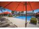 Lounge chairs sit around a pool with clear blue water, creating a vacation oasis with an orange umbrella for shade at 12022 Medley Ter, Lakewood Ranch, FL 34211
