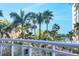 A relaxing balcony with palm tree views featuring comfortable wicker chairs and a glass railing at 1300 Benjamin Franklin Dr # 304, Sarasota, FL 34236