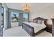 The main bedroom displays a decorative chandelier, large windows, and an ornate wooden bed frame with quality linens at 1300 Benjamin Franklin Dr # 304, Sarasota, FL 34236