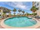 A luxurious swimming pool surrounded by palm trees and comfortable lounge chairs under a bright sky at 1300 Benjamin Franklin Dr # 304, Sarasota, FL 34236