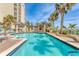 A luxurious swimming pool with nearby cabanas surrounded by palm trees and lounge chairs at 1300 Benjamin Franklin Dr # 304, Sarasota, FL 34236
