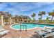Beautiful building featuring a luxury pool, lounge chairs and tables, and swaying palm trees under a sunny sky at 1300 Benjamin Franklin Dr # 304, Sarasota, FL 34236