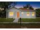 Inviting single-story home featuring a bright orange front door and a well-maintained lawn at dusk at 1301 12Th S St, St Petersburg, FL 33705