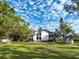 Beautiful backyard featuring lush green lawn, mature trees, and a charming modern home with dual decks at 1471 Arcadia Ave, Sarasota, FL 34232