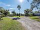 Long gravel driveway leads to a home with a scenic view of a lush lawn and pond at 1471 Arcadia Ave, Sarasota, FL 34232