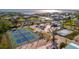 Aerial view showcasing well-maintained tennis courts with lush landscaping near waterfront homes and stunning ocean views at 15 Seaside Ct, Holmes Beach, FL 34217