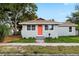 Inviting single-story home boasts a light-blue exterior, orange front door and a neatly maintained lawn at 1739 16Th S Ave, St Petersburg, FL 33712