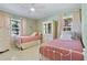 Charming bedroom featuring two twin beds with white frames, pink bedding, and natural light from the windows at 1870 Jasmine Dr, Sarasota, FL 34239