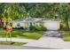 Charming yellow home featuring a well-manicured lawn, brick driveway, and lush landscaping at 1870 Jasmine Dr, Sarasota, FL 34239