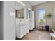 Bathroom with double sink, brown tile floor, and a window at 2305 Pine Ter, Sarasota, FL 34231