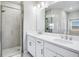 Bright bathroom features double sinks, vanity with white cabinets and glass shower at 23445 Collina Way # 10103, Port Charlotte, FL 33980