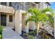 Unit entrance with a black door, lush landscaping including palm tree and visible staircase at 23445 Collina Way # 10103, Port Charlotte, FL 33980