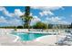 Beautiful community pool with lounge chairs and shade trees on a sunny day with blue skies and white clouds at 4133 Heron Way # E202, Bradenton, FL 34205
