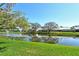 Scenic water view with a fountain, mature trees, and lush green grass behind residential homes at 4149 Salernes Ave # 3048, Sarasota, FL 34233