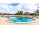 Large community pool with steps for entry, surrounded by chairs and umbrellas at 4225 66Th Street W Cir, Bradenton, FL 34209