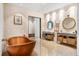Enjoy this luxurious bathroom featuring dual sinks, a soaking tub, stone accent walls, and natural light at 49 Osprey Point Dr, Osprey, FL 34229