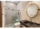 Modern bathroom featuring a stone sink, round mirror, and glass shower at 49 Osprey Point Dr, Osprey, FL 34229