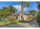 Inviting home front with mature landscaping, including palm trees and lush lawn at 49 Osprey Point Dr, Osprey, FL 34229