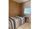 Simple bedroom featuring tile floors, light wood paneling, and small table next to the bed at 5791 Holiday Park Blvd, North Port, FL 34287