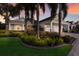 Beautifully landscaped home featuring lush greenery, palm trees, and a charming facade at sunset at 581 Mast Dr, Bradenton, FL 34208