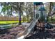 Community playground with slide, climbing structure, and lush trees, perfect for families at 581 Mast Dr, Bradenton, FL 34208