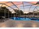 Relaxing pool area with screened enclosure, lounge chairs, tropical landscaping, and colorful sunset views at 581 Mast Dr, Bradenton, FL 34208