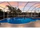 Relaxing pool area with screened enclosure, lounge chairs, tropical landscaping and sunset sky at 581 Mast Dr, Bradenton, FL 34208