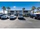 Exterior view of the building and parking, with palm trees, offering ample parking spaces at 600 Manatee Ave # 114, Holmes Beach, FL 34217