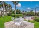Outdoor dining area with patio furniture near a tennis court and lush greenery at 600 Manatee Ave # 114, Holmes Beach, FL 34217