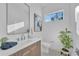 Modern bathroom featuring a floating vanity, rectangular mirror, and a window offering natural light and a green plant at 603 Tremont St, Sarasota, FL 34242