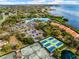 Aerial view of tennis courts, clubhouse, and parking area with a water view at 6430 Sun Eagle Ln # 103, Bradenton, FL 34210