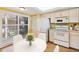 Bright kitchen with white appliances, hardwood floors, and sunlit dining area near the shuttered windows at 6430 Sun Eagle Ln # 103, Bradenton, FL 34210