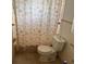 Compact bathroom with a toilet and a shower featuring a decorative shower curtain at 704 Chippy Ln, Nokomis, FL 34275
